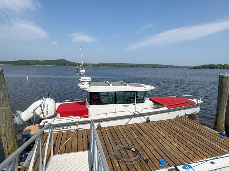 Slide: The Image of 2021 Axopar 28 CABIN boat docked by a wooden pier on a sunny day. - 25
