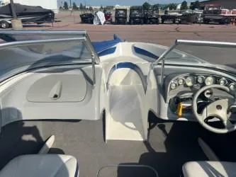 Slide: The Image of 2005 Bayliner 205 Bowrider interior with steering wheel and dashboard, parked outdoors. - 2