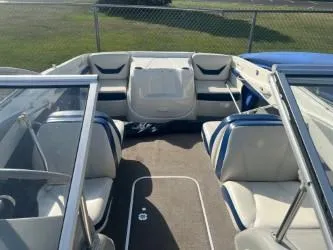 Slide: The Image of 2005 Bayliner 205 Bowrider interior with white and blue seating, open bow design. - 4