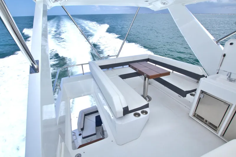 Slide: The Image of Flybridge view of 2018 Cruisers Yachts 54 Fly, featuring sleek seating and ocean backdrop. - 11