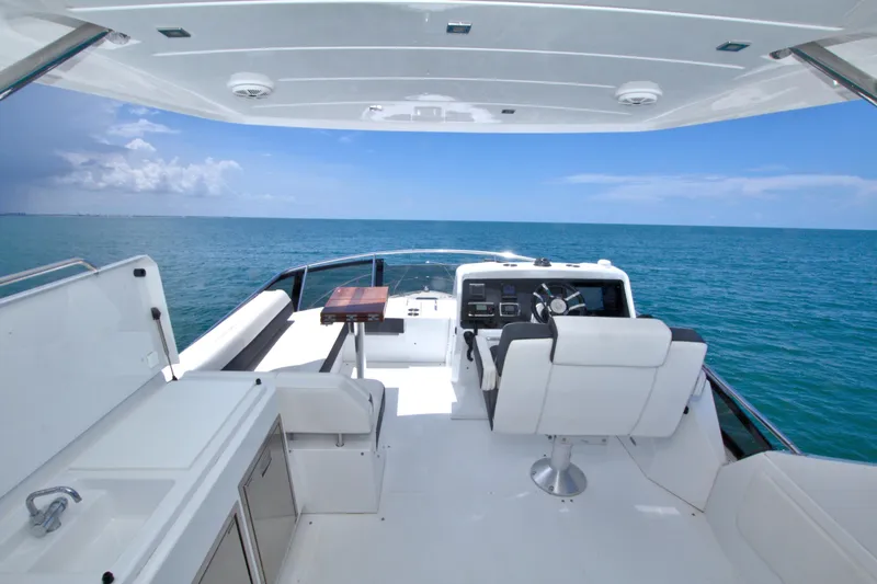 Slide: The Image of 2018 Cruisers Yachts 54 Fly bridge with ocean view, featuring helm and seating area. - 13