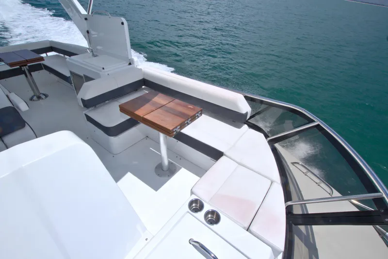 Slide: The Image of 2018 Cruisers Yachts 54 Fly deck with seating and wooden tables on open water. - 17