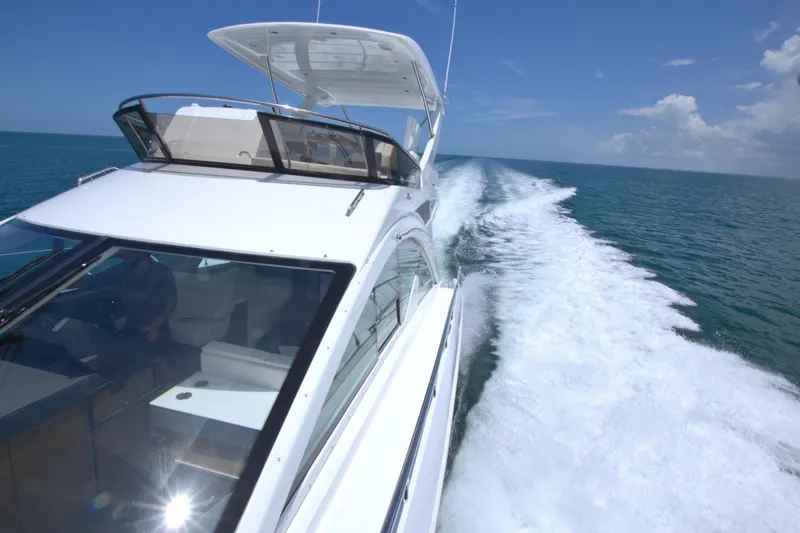 Slide: The Image of 2018 Cruisers Yachts 54 Fly cruising on open water under clear blue skies. - 28