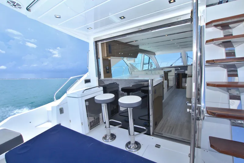 Slide: The Image of 2018 Cruisers Yachts 54 Fly interior with ocean view, featuring modern seating and sleek design. - 33