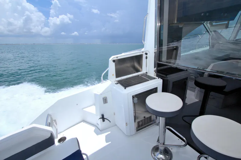 Slide: The Image of 2018 Cruisers Yachts 54 Fly deck with seating and grill, cruising on open water. - 34