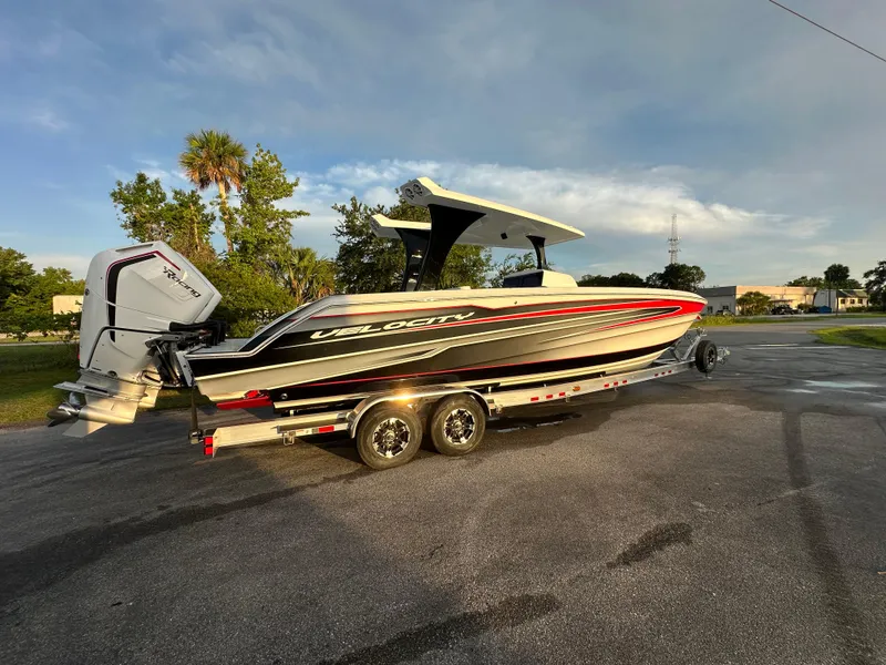 The Image of 2026 Velocity 330 CC boat on trailer, parked outdoors under a clear sky. - 1