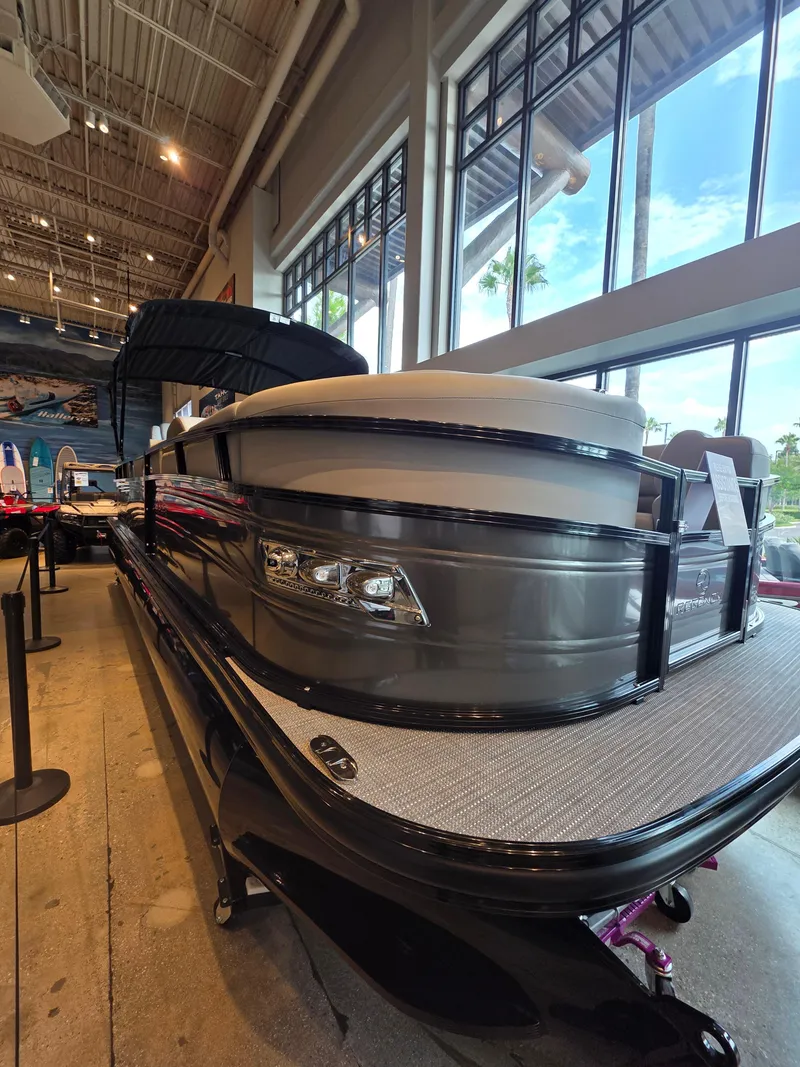 The Image of 2025 Regency 250 LE3 pontoon boat displayed indoors with large windows and high ceiling. - 0