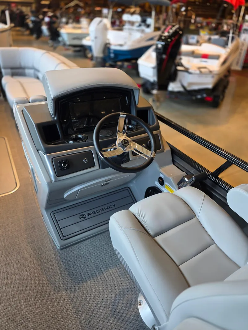 Slide: The Image of 2025 Regency 250 LE3 boat interior with steering wheel and seating, displayed in showroom. - 2