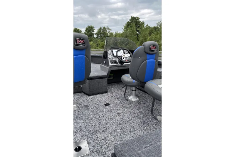 Slide: The Image of 2025 Ranger VS1882SC Reata boat interior with blue and gray seating, steering console, and lush greenery backdrop. - 3