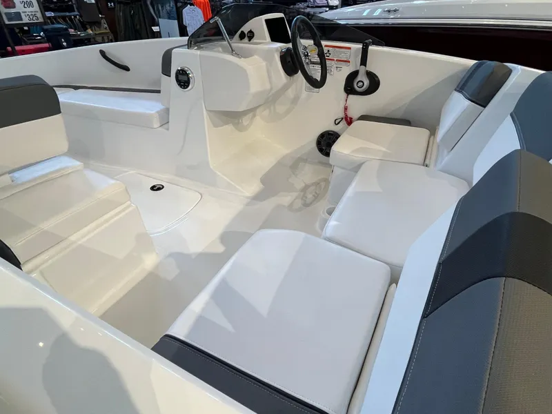 Slide: The Image of Interior of 2025 Tahoe T16 boat with white and gray seating, steering wheel, and controls. - 2