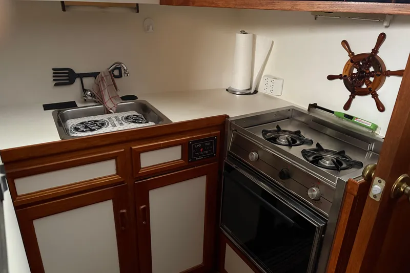 Slide: The Image of Compact kitchen in a 1988 Cooper Prowler boat with stove, sink, and nautical decor. - 53