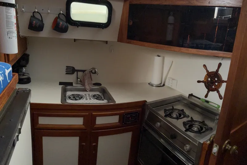 Slide: The Image of Compact kitchen in 1988 Cooper Prowler boat with stove, sink, and wooden cabinetry. - 54