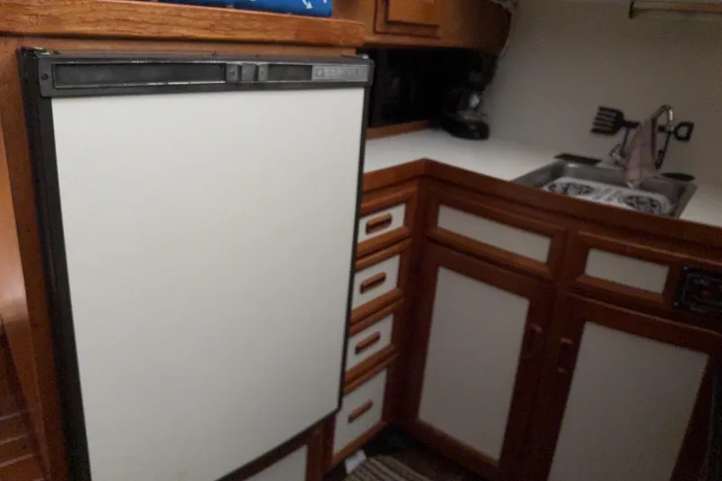 Slide: The Image of Compact kitchen area in a 1988 Cooper Prowler boat, featuring a fridge and sink. - 55