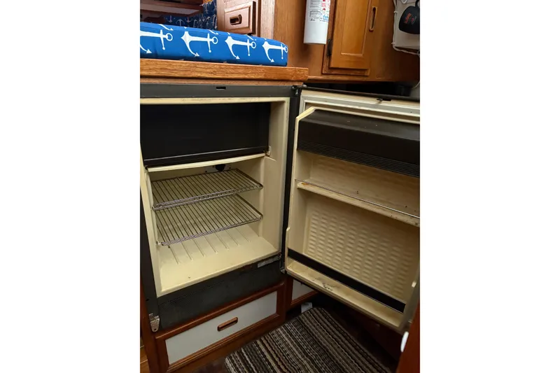 Slide: The Image of Open refrigerator in 1988 Cooper Prowler boat interior, featuring wooden cabinetry and nautical decor. - 57