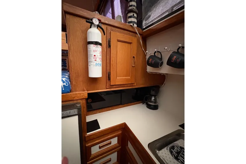 Slide: The Image of 1988 Cooper Prowler kitchen area with wooden cabinets, fire extinguisher, and coffee maker. - 59