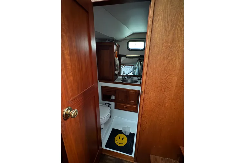 Slide: The Image of 1988 Cooper Prowler boat bathroom with wooden door, sink, and smiley face mat. - 62