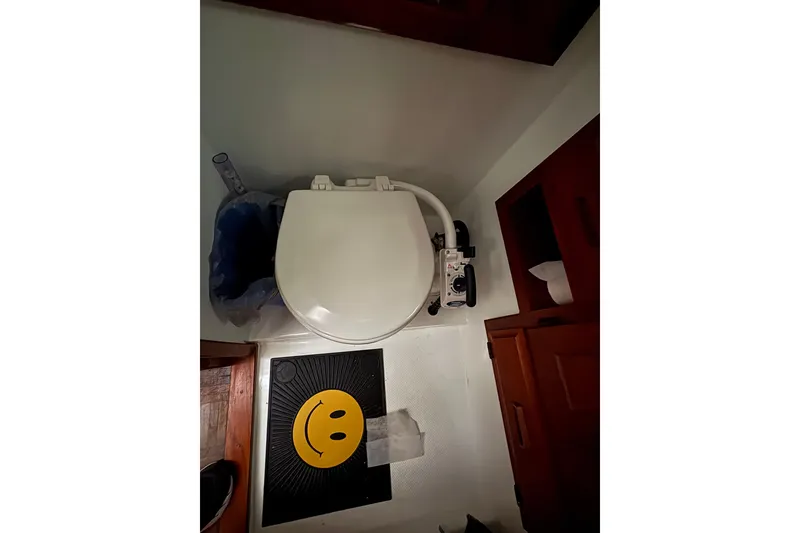 Slide: The Image of 1988 Cooper Prowler bathroom with toilet, smiley face mat, and wooden cabinets. - 63
