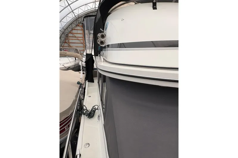 Slide: The Image of 1988 Cooper Prowler boat in storage, side view with covered deck and coiled rope. - 73