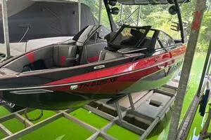 Slide: The Image of 2022 Malibu Wakesetter 23 LSV boat in dock, red and black design, side view. - 2