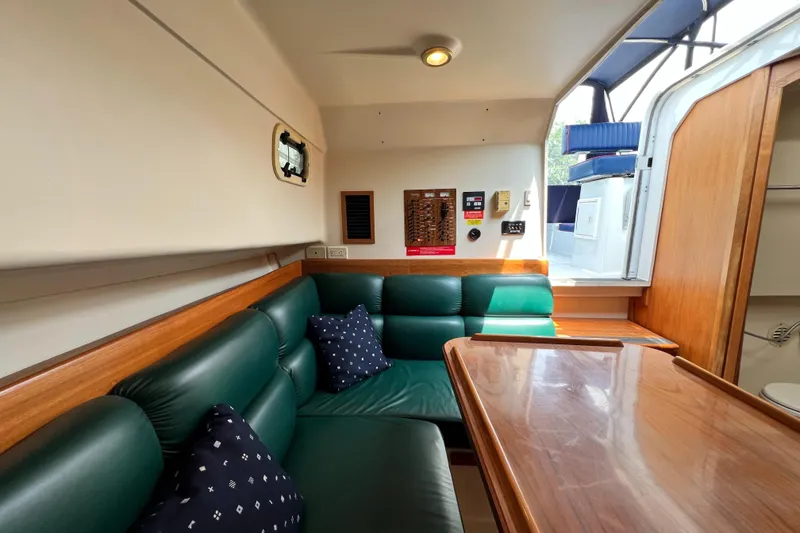 Slide: The Image of Interior of 2001 Mainship 34 PILOT with green seating and wooden table. - 30