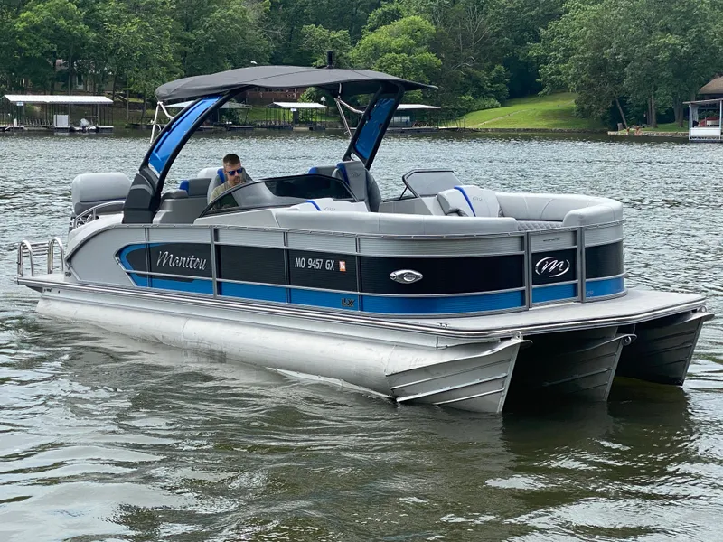 The Image of 2022 Manitou 25 LX SRW SHP pontoon boat on a lake with lush greenery. - 1