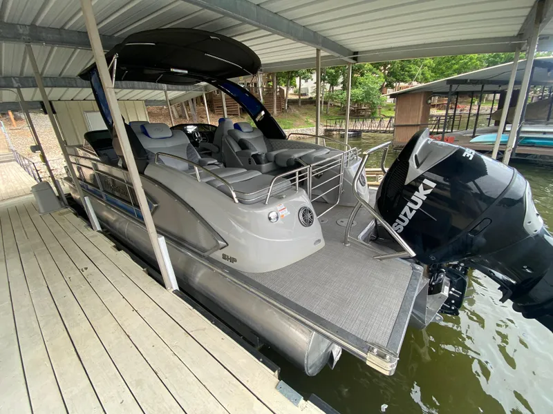 Slide: The Image of 2022 Manitou 25 LX SRW SHP pontoon boat docked with Suzuki outboard motor. - 12