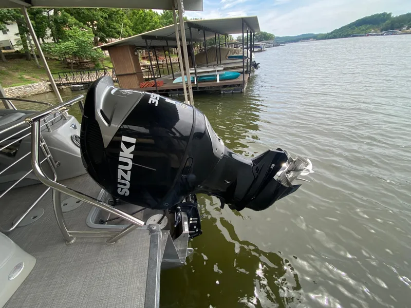 Slide: The Image of 2022 Manitou 25 LX SRW SHP boat with Suzuki outboard motor on a lake. - 13