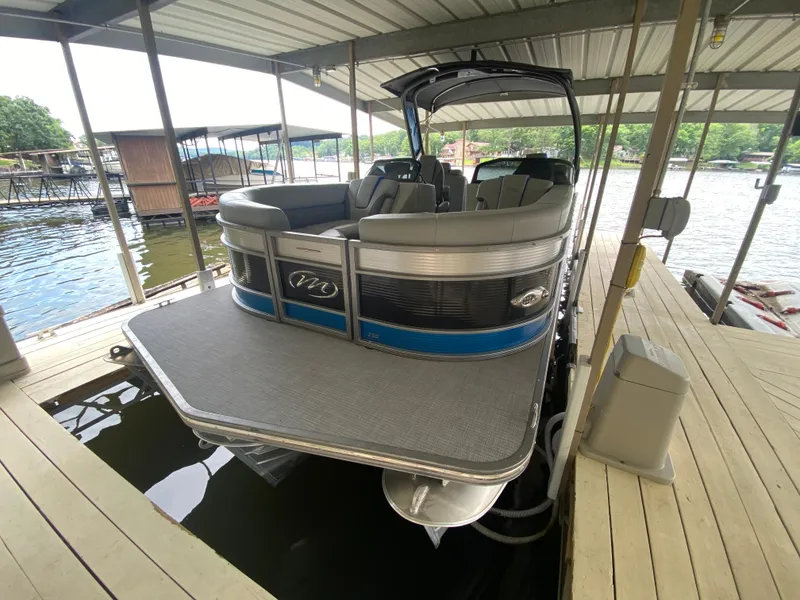 Slide: The Image of 2022 Manitou 25 LX SRW SHP pontoon boat docked under a covered marina. - 15