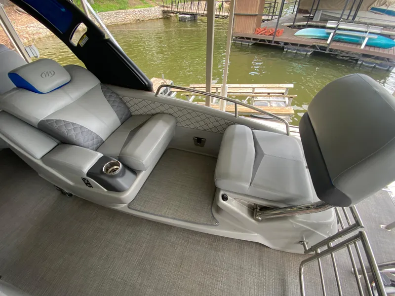 Slide: The Image of 2022 Manitou 25 LX SRW SHP boat interior with luxurious seating by the water. - 18