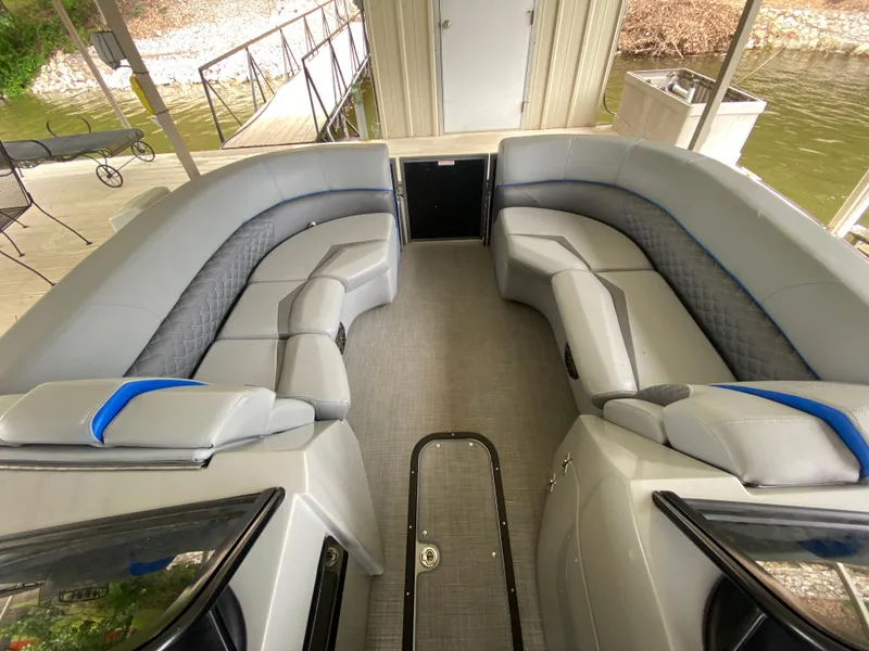 Slide: The Image of 2022 Manitou 25 LX SRW SHP pontoon boat interior with gray seating and blue accents. - 24