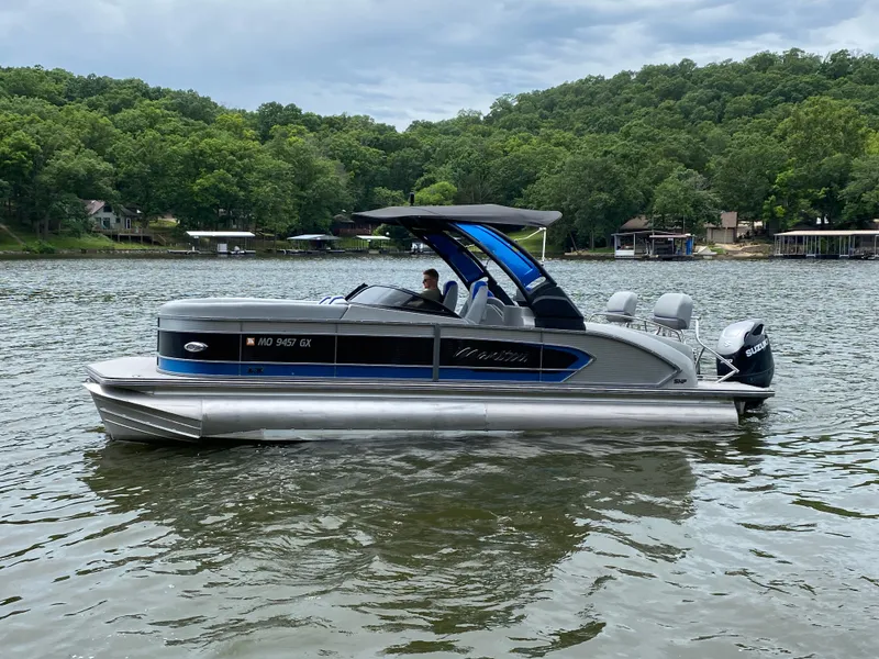 Slide: The Image of 2022 Manitou 25 LX SRW SHP pontoon boat on a scenic lake. - 4