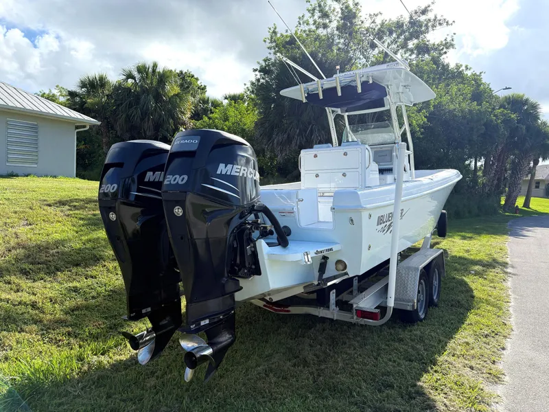 Slide: The Image of 2015 Bluewater 2550 boat with dual Mercury 200 engines on a trailer, parked outdoors. - 17