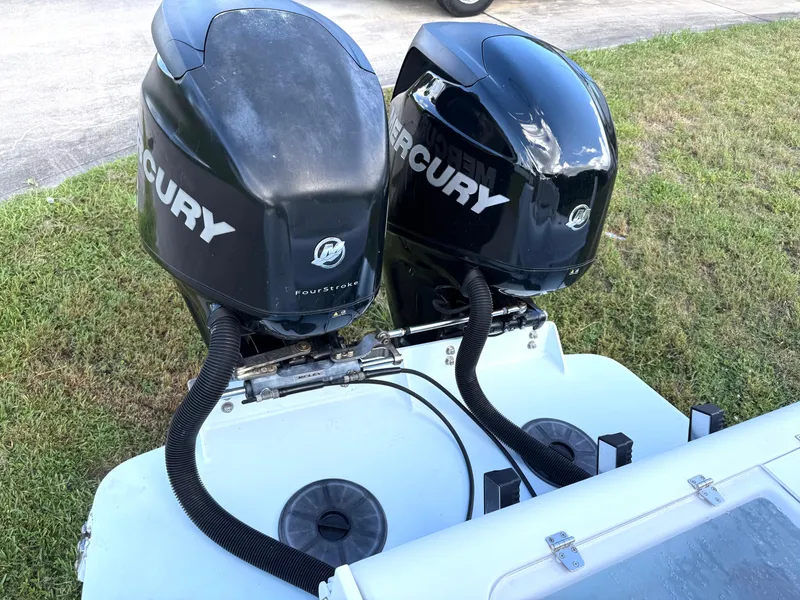 Slide: The Image of Twin Mercury outboard engines on a 2015 Bluewater 2550 boat, parked on grass. - 18