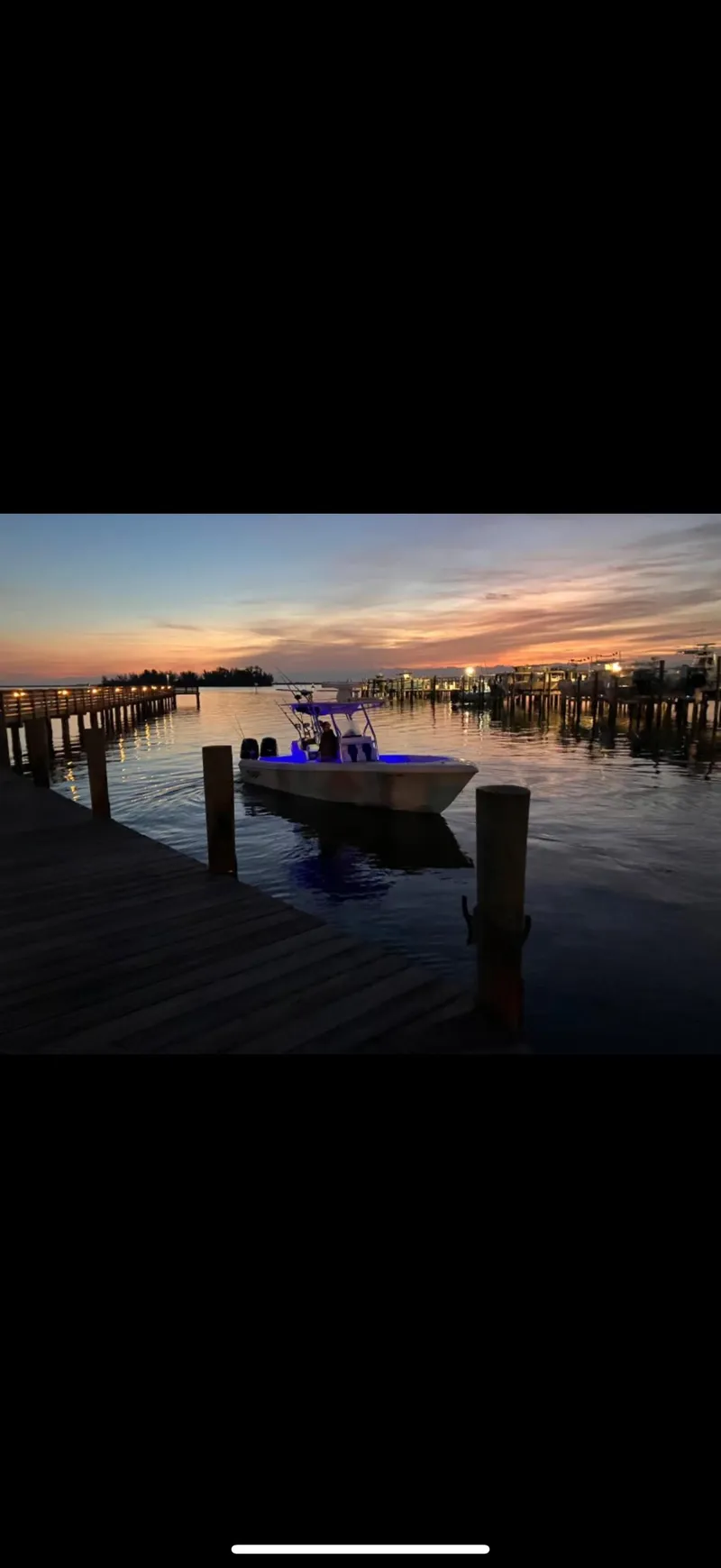 Slide: The Image of 2015 Bluewater 2550 boat docked at sunset, surrounded by calm water and piers. - 19