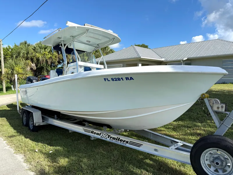 Slide: The Image of 2015 Bluewater 2550 boat on trailer, parked outdoors under clear blue sky. - 3
