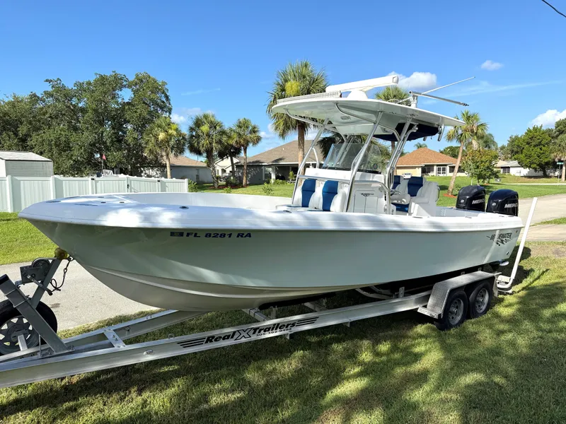 Slide: The Image of 2015 Bluewater 2550 boat on trailer, parked outdoors with palm trees in background. - 5