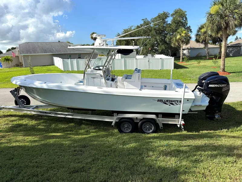 Slide: The Image of 2015 Bluewater 2550 boat on trailer with Mercury engine, parked on grass. - 6