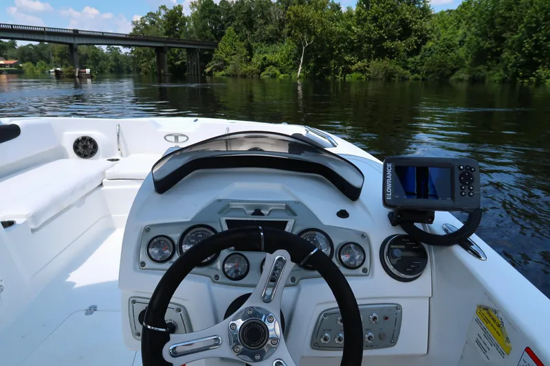 Slide: The Image of 2017 Tahoe 2150 boat dashboard with steering wheel and navigation system on a calm river. - 16