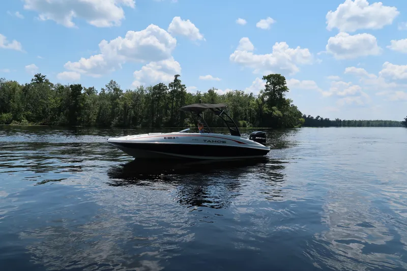 Slide: The Image of 2017 Tahoe 2150 boat cruising on a serene lake under a partly cloudy sky. - 3