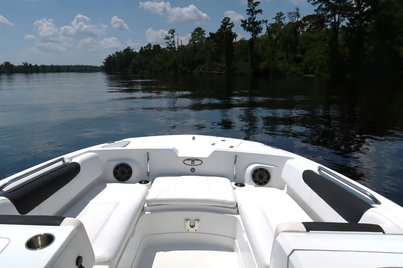 Slide: The Image of 2017 Tahoe 2150 boat interior with white seating, on a calm lake with trees. - 5