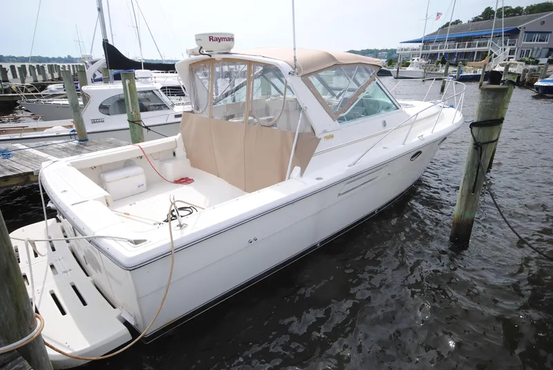 The Image of 1996 Tiara Yachts 3100 Open docked at marina, featuring beige canopy and spacious deck. - 0