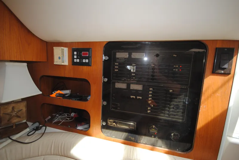 Slide: The Image of Electrical panel inside 1996 Tiara Yachts 3100 Open, featuring control switches and storage shelves. - 15