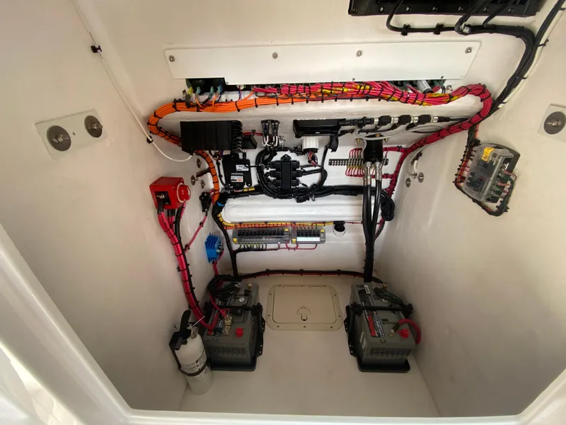 Slide: The Image of Electrical compartment of 2026 Reef Runner 230 boat, featuring organized wiring and dual batteries. - 16