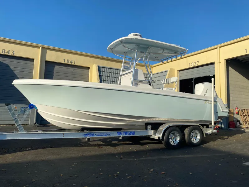 Slide: The Image of 2026 Reef Runner 230 boat on trailer, parked outside storage units. - 6