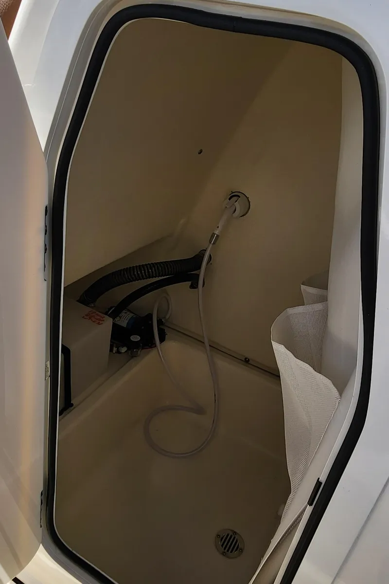 Slide: The Image of 2025 Pioneer 202 Islander boat interior compartment with hose and drain. - 16