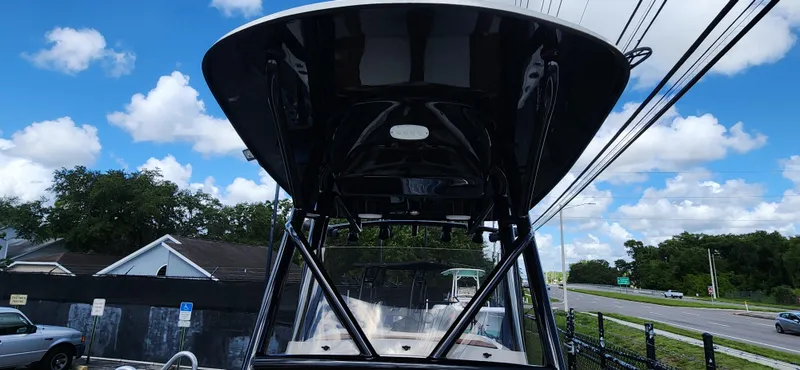 Slide: The Image of 2025 Pioneer 202 Islander boat with T-top, parked outdoors under a blue sky. - 19