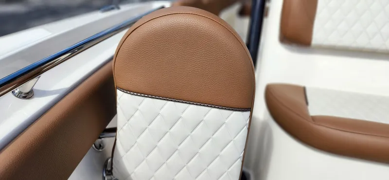 Slide: The Image of 2025 Pioneer 202 Islander boat interior with brown and white quilted leather seating. - 21