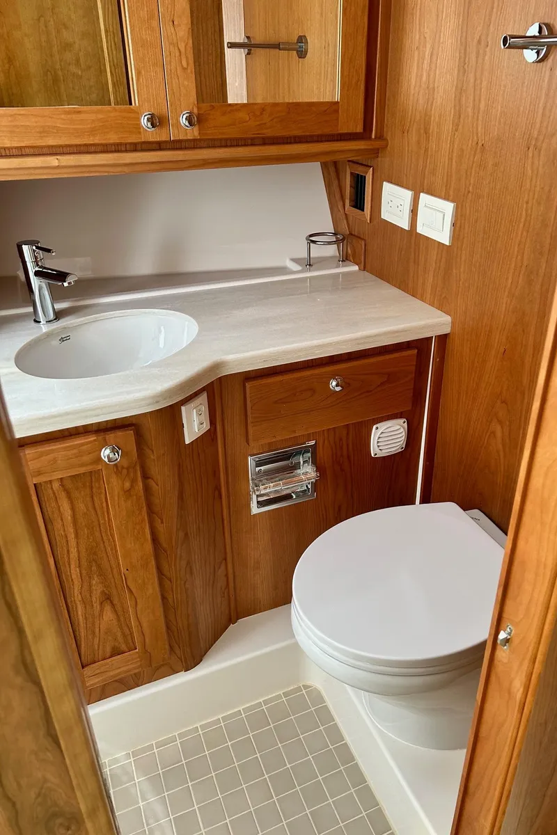 Slide: The Image of 2026 Sabre 45 Salon Express bathroom with wooden cabinetry and modern fixtures. - 13