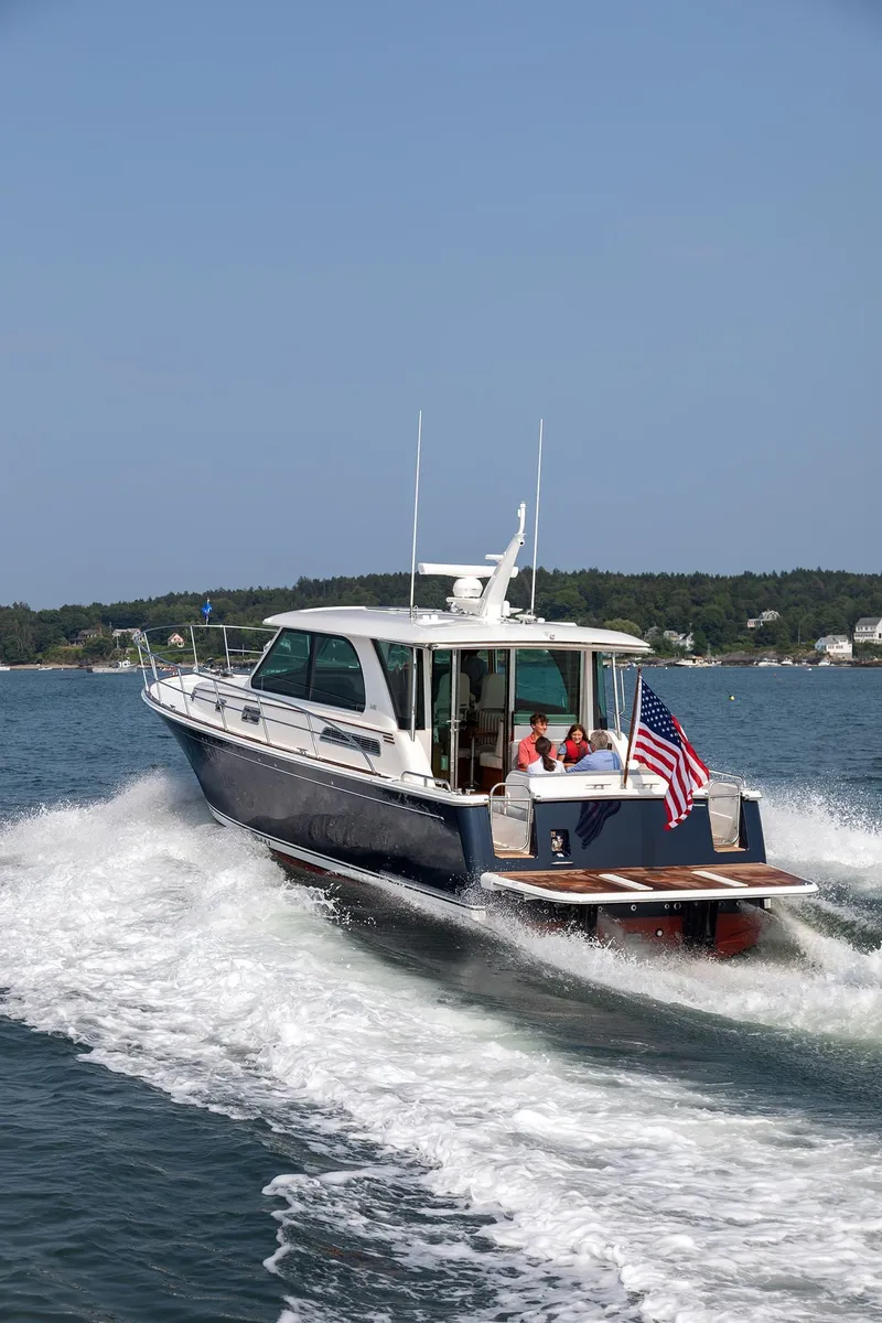 Slide: The Image of 2026 Sabre 45 Salon Express cruising on a scenic lake with passengers onboard. - 2