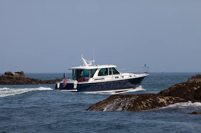 Slide: The Image of 2026 Sabre 45 Salon Express cruising between rocky outcrops on a clear day. - 3